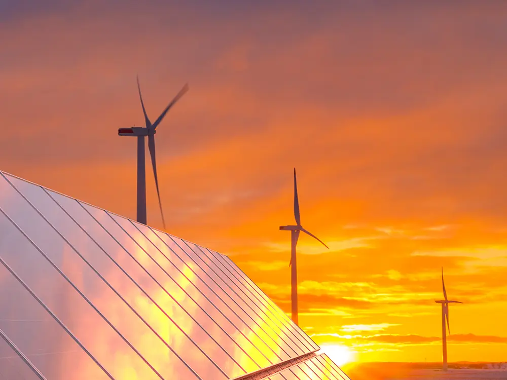Eoliennes et panneaux solaires sur un fond de coucher de soleil